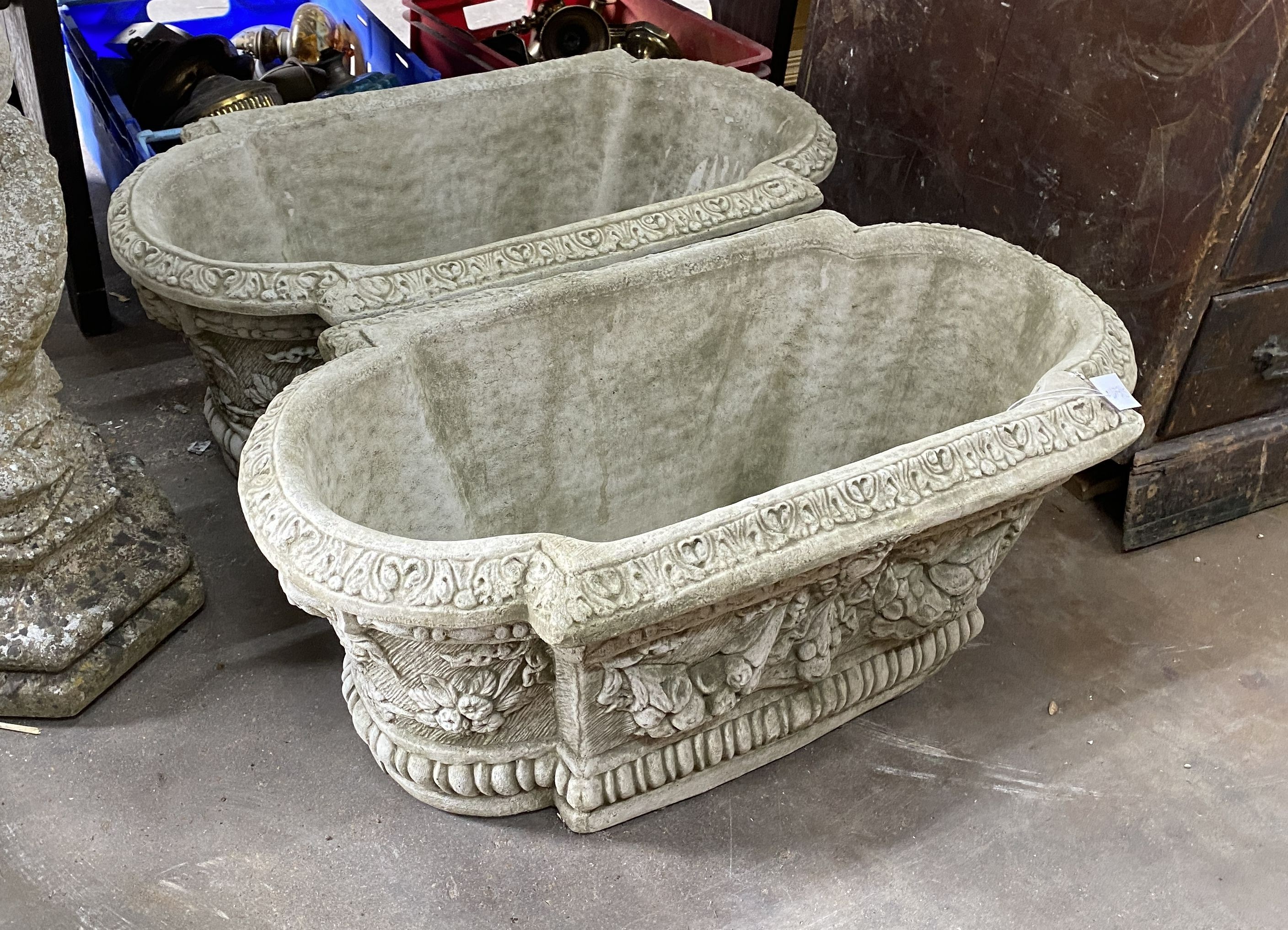 A pair of shaped oval reconstituted stone garden planters with floral swag bodies, width 82cm, depth 42cm, height 34cm
